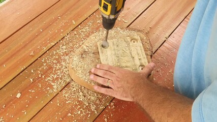 Video of man making a hole in a piece of wood with a drill using a flat wood drill bit. Man using a tool with battery. Man using a spade bit to drill a hole in a wood.