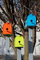 A group of colorful birdhouses made from mail boxes.
