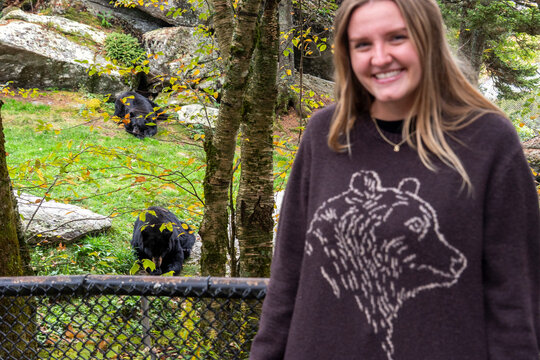 woman smiling by animal enclosure, casual scene showing woman engaging with wildlife conservation