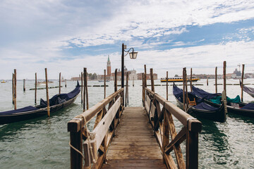 Fototapeta premium Venice gondolas moored at wooden pier overlooking San Giorgio Maggiore