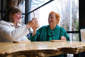 woman and adult daughter elderly woman Portrait of old peasant woman with smiling daughter wearing typical Colombian clothes. Women with brown skin. cafe drinking coffee