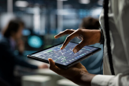 Close up of data center computer scientist using tablet, deploying servers and network hardware. IT specialist in server farm using device to manage large scale IT infrastructure