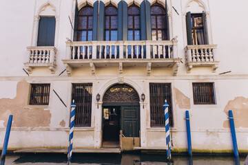 Venetian building fronting canal with striped boat poles