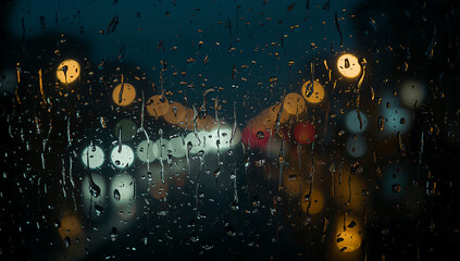 Fototapeta premium Raindrops on a Window with City Lights Reflections at Night