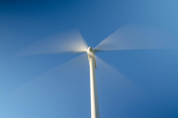 Naklejka premium Moving wind turbine blades blurred motion clean energy technology copy space.