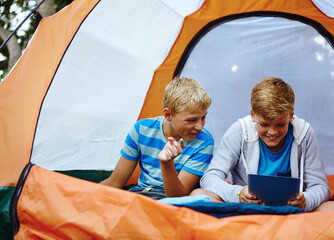 Kids, tablet and boys in tent, smile and typing with online game, relax and entertainment. Camping,...