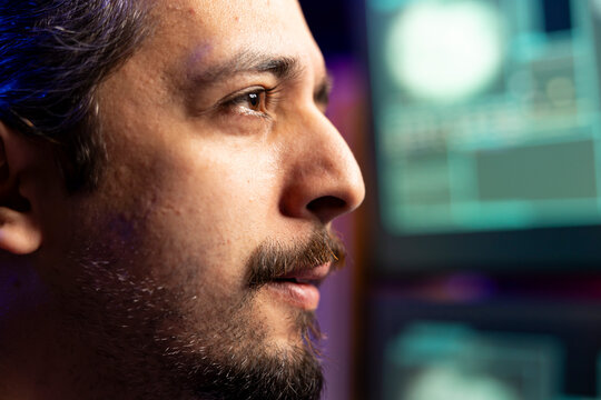 Evil man in cyber safehouse exploiting servers for stolen data profit. Close up focused hacker in base of operations using PC to gain unauthorized network access, targeting unpatched connections