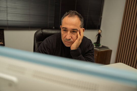 Man resting his head on hand while looking at a computer screen