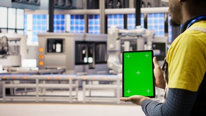 Smart factory expert uses green screen tablet to implement automated workflows. Industry 4.0 plant technician integrates sensors into production using chroma key device, camera A close up