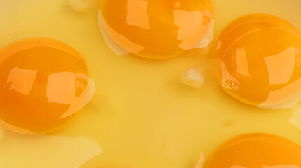 Raw eggs with bright yolks and transparent whites, top view. Fresh cracked eggs ready for cooking or baking. Closeup of egg yolks in natural state. Raw egg concept for kitchen and food preparation