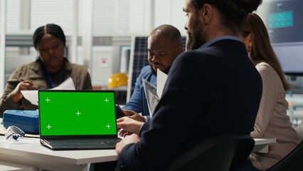 Fototapeta premium Photovoltaics factory team looking at green screen laptop, improving development efficiency. Solar panels manufacturing plant researchers studying how to harness sun power using mockup notebook