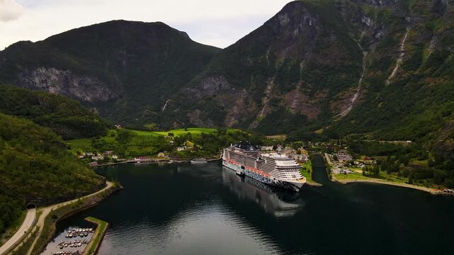 Aerial view of a cruise ship nestled in the fjord waters surrounded by lush green mountains, Flam, Vestland, Norway.