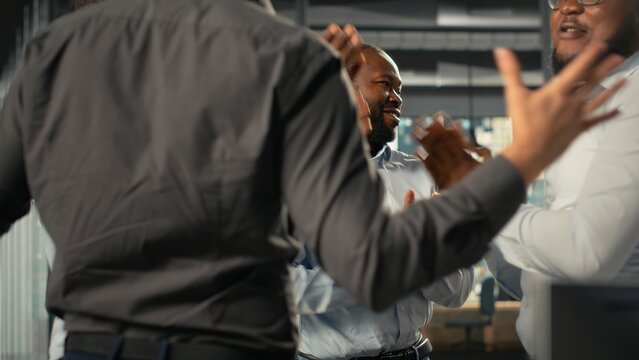 Professional coworkers uniting hands after successful tasks completion, clapping hands and congratulating on performance metrics reports. Collaborative corporate workspace.