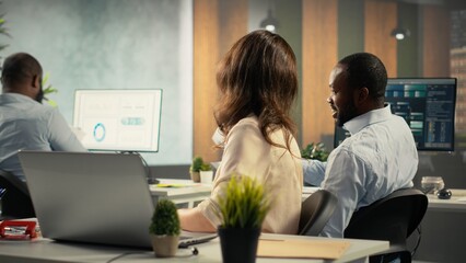 Employees engaged in business intel and analytics using data diagrams in a corporate office, staff reviews projections and reports to improve overall company strategy.