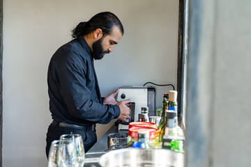 Barista preparing espresso using coffee machine in well-lit kitchen setting.