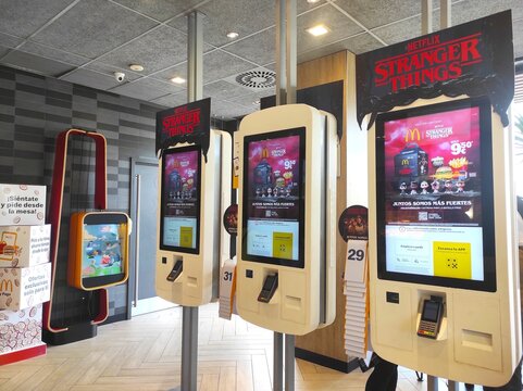 Benidorm, Spain - November 15, 2025: Interactive self-service kiosks featuring Netflix Stranger Things promotion at McDonald's restaurant with vibrant digital displays
