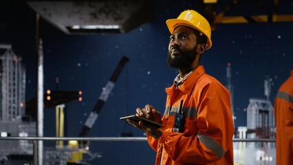 Industrial engineer inspect offshore drilling rig systems using tablet to monitor emissions while extracting natural gas and petroleum. Ensuring efficient oil production for the industry.