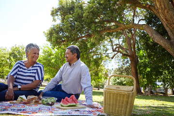 Smile, senior couple and picnic at park with love, romantic date and bonding together. Happy, elderly people and chilling with food for anniversary, relax on grass and commitment on holiday in nature