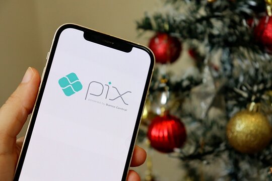 Salvador, Brazil - December 1st, 2025: Brazilian PIX logo with Christmas tree background, symbolizing digital payment gifts. 