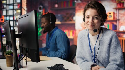 Portrait of smiling call center agent next to coworkers tracking shipments in office, solving...