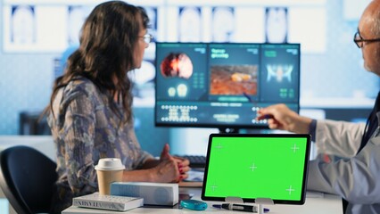 Old patient and specialist at check up visit next to chroma key display, discuss about prescription medicine and recovery plan. General practitioner offers advice and support to a woman. Camera B.