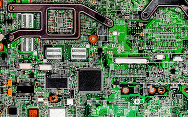 Close-up view of a laptop motherboard showing microchips, circuits, and soldered components with intricate green pathways and detailed electronic architecture in high-resolution macro.