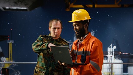 Military officer in camouflage uniform uses walkie talkie on offshore platform, coordinating escort duty, crisis response and coastal defense to safeguard oil rig operations at sea.