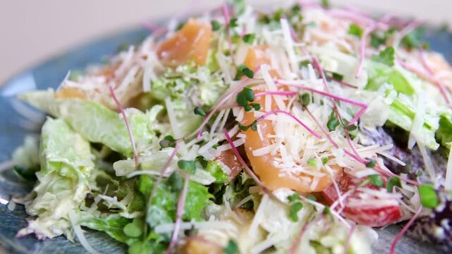 Parmesan salad greens Traditional caesar salad in a white bowl with leaves and a sauce boat and parmesan. Selected focus. High quality 4k footage
