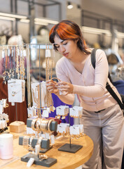 Customer inspect at products in store and pick out accessories. Young woman search and choose bracelet. Market conjuncture, ratio of supply and demand