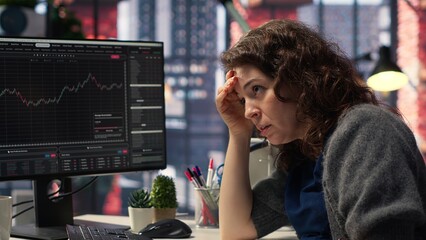 Day trader feeling worried and stressed looking at monetary losses, analyzing stock price trends on pc. Exasperated woman losing shares and dealing with market crash, trading decisions. Camera B.