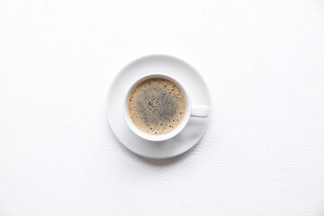 Black coffee with foam in a white cup on a white table