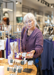 Eldery woman buyer choosing jewelry in accessories store
