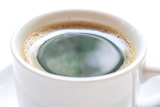 Close up Black coffee with foam in a white cup on a white table - Powered by Adobe