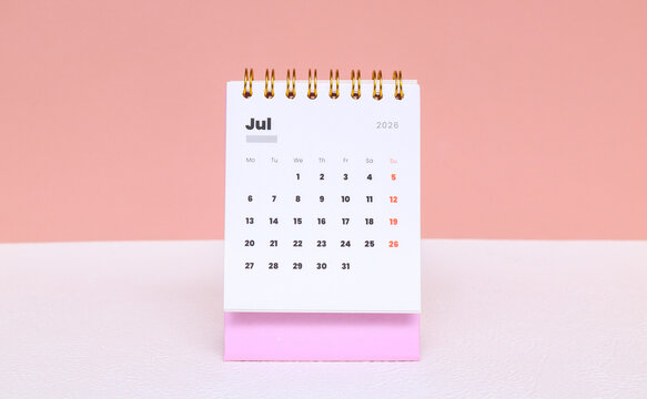 July 2026 in the pink calendar on the table isolated on pink background. A desk calendar showing July 2026 placed on a table with a pink background. Minimal and aesthetic workspace concept.