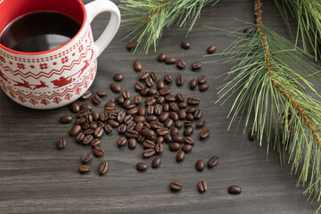 Christmas mug of coffee with coffee beans on a dark background with border of evergreen branch