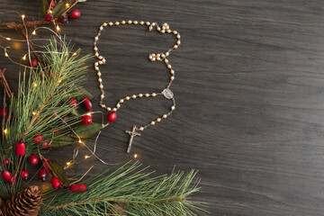Rosary prayer beads and a Christmas border on dark wood with copy space