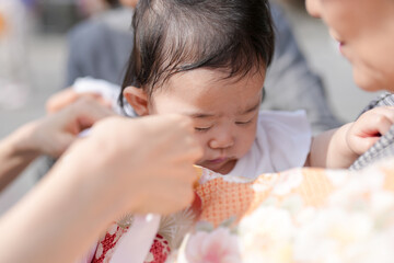 A woman is holding a baby and fixing its hair. The baby is crying and the woman is trying to calm...