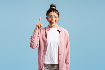 Woman with glasses getting idea, pointing finger up, finding solution looking happy