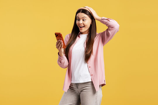 Young woman reacting with surprise and excitement while reading good news on phone