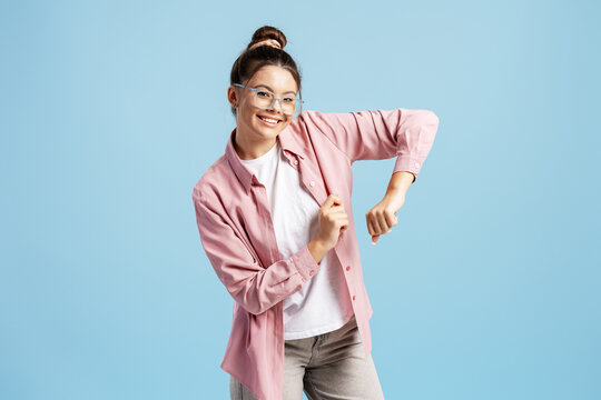 Young woman dancing, smiling with happiness and positive energy on blue background