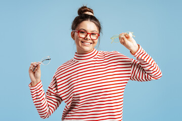 Young woman choosing new eyewear, holding different stylish glasses frames