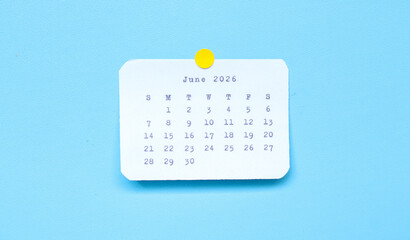 A paper sticker showing June 2026 placed on a blue background. A june 2026 sticker attached to a blue background. Minimal and clean calendar concept.