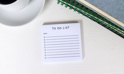 To do list sheet on desk surrounded by books, glasses, clock, coffee. Checklist of tasks to complete. Business planning, design and reminder. To do list and list of numbers on a table.