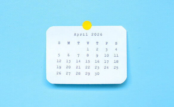 A paper sticker showing April 2026 placed on a blue background. A April 2026 sticker attached to a blue background. Minimal and clean calendar concept.