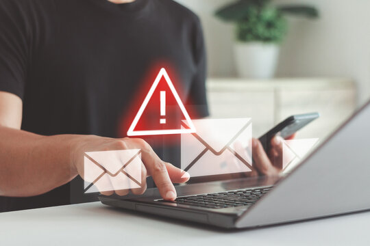 Person checking suspicious emails on a laptop with a warning alert icon, illustrating cybercrime risks, phishing threats, data security awareness and digital protection in modern online communication. - Powered by Adobe