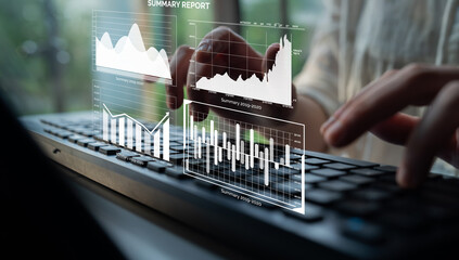 A business professional analyzes digital graphs and charts while typing on a keyboard in a modern office. The scene represents data analysis and reporting. Impute
