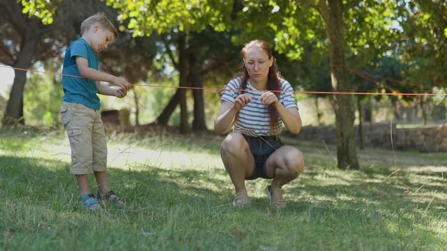 Mother and son playing a rope game in a sunny park