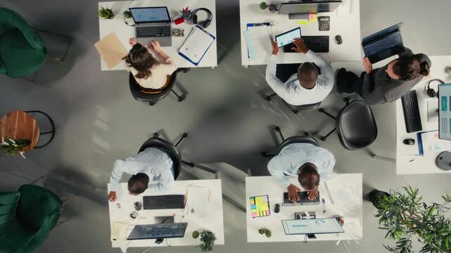 Top down view zoom in of professional people analyzing documents and graphs for risk assessment. Diverse work team collaborates on report writing and forecasting in office. Camera A.