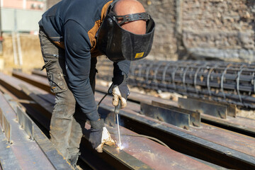 Construction worker welding steel beams at a building site