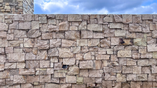 Full-frame texture background of a wall constructed from small, rough, stacked natural stone blocks (ashlar masonry). Concept for architecture, durability, exterior design, and rustic pattern.